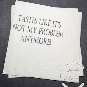 May include: A stack of white paper napkins with the text "TASTES LIKE IT'S NOT MY PROBLEM ANYMORE!" printed in black. The napkins have a textured surface and are on a dark background. The Sparkle & Sparrow copyright is visible.