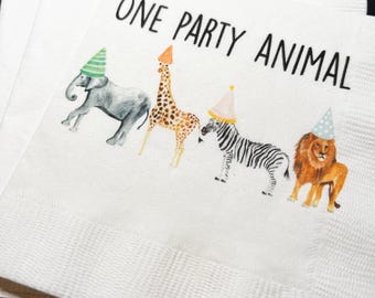 May include: White paper napkins with the text "ONE PARTY ANIMAL" and illustrations of an elephant, giraffe, zebra, and lion, each wearing a party hat. The napkins are stacked.