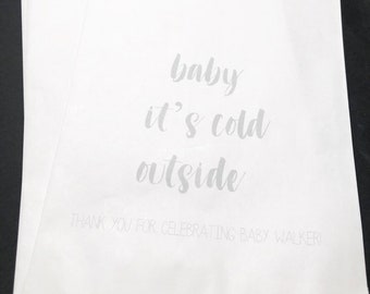 May include: White paper gift bags with the text "baby it's cold outside" and "Thank you for celebrating baby Walker!" printed on them.