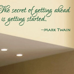 May include: A black leather bench with a brown wall and a large abstract painting behind it. The quote "The secret of getting ahead is getting started. --Mark Twain" is written on the wall above the bench.