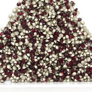 May include: A pile of red and silver rhinestones in a triangular shape.