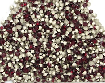May include: A pile of red and silver rhinestones in a triangular shape.