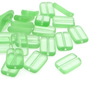 May include: A pile of light green glass beads with a rectangular shape and a small groove down the center. The beads are translucent and have a frosted finish.