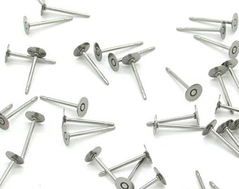 May include: A large quantity of silver-toned earring posts with flat round backs. The posts are scattered on a white surface.