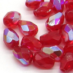 May include: A group of 20 red iridescent glass beads in a teardrop shape. The beads have a faceted design and are approximately 10mm in length.