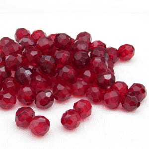 8mm faceted round plastic beads are translucent ruby red acrylic and a traditional choice for kids' crafts such as Christmas ornaments and friendship bracelets.