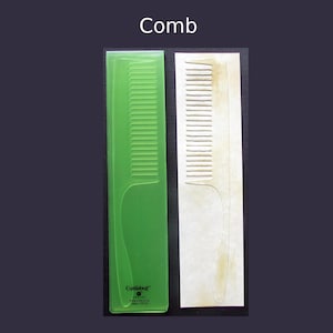 May include: A translucent green rectangular plastic embossing folder featuring a comb design and the text Cuttlebug, alongside a white paper strip showing the embossed comb impression with a light brown tint on the teeth and handle area.