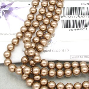 May include: A strand of bronze-colored round glass beads. The beads are approximately 8mm in diameter and have a smooth, shiny finish. The beads are strung on a clear thread and are ready to be used for jewelry making or other craft projects.