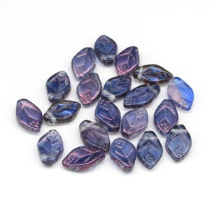 May include: A collection of 18 iridescent glass beads in shades of blue and purple. The beads are shaped like leaves and have a textured surface.