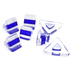 May include: A set of six clear glass dice with blue stripes. The dice are in the shape of a cube and a triangle.