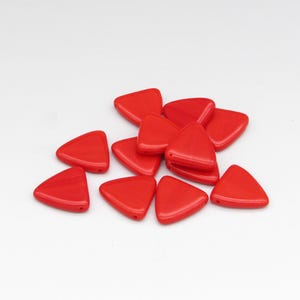 May include: A collection of bright red, triangular beads scattered on a white surface. Each bead has a smooth, glossy finish and a small hole for stringing. These beads are ideal for jewelry making or craft projects.