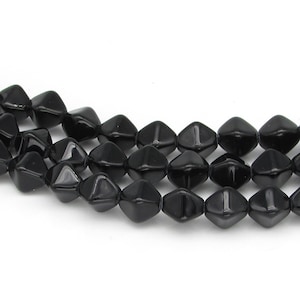 May include: A strand of black faceted glass beads. The beads are shaped like a diamond with a pointed top and bottom. The beads are strung on a clear thread.