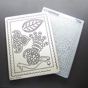 May include: A silver metal die-cutting template featuring a decorative design of a stylised bird with a leaf. The template is labelled "Cutterbug" and "Provo Craft".