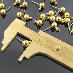Post earring findings have a 6 millimeter shiny, gold plated brass ball and loop attached to a  7/16 inch stainless steel post.
