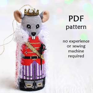 Op de afbeelding: Een grijze muis die een rood en gouden koningskostuum draagt met een witte bontkraag. De muis houdt een zwaard vast en is een kerstversiering. PDF-patroon inbegrepen. Geen ervaring of naaimachine vereist.