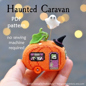May include: A cross-stitch pattern for a haunted caravan shaped like a pumpkin. The caravan has a ghost, a witch's hat, and a green stem on top. The text on the image reads "Haunted Caravan PDF pattern no sewing machine required".