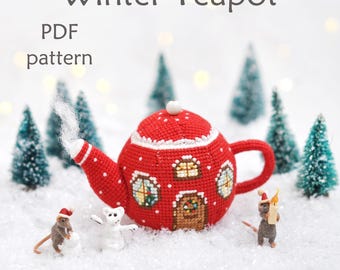 Op de afbeelding: Een rode, handgemaakte theepot met witte stippen en een witte rand, die lijkt op een winterhuisje. De theepot heeft een handvat en een tuit, met miniatuurfiguren en de tekst "Winter Teapot PDF pattern".
