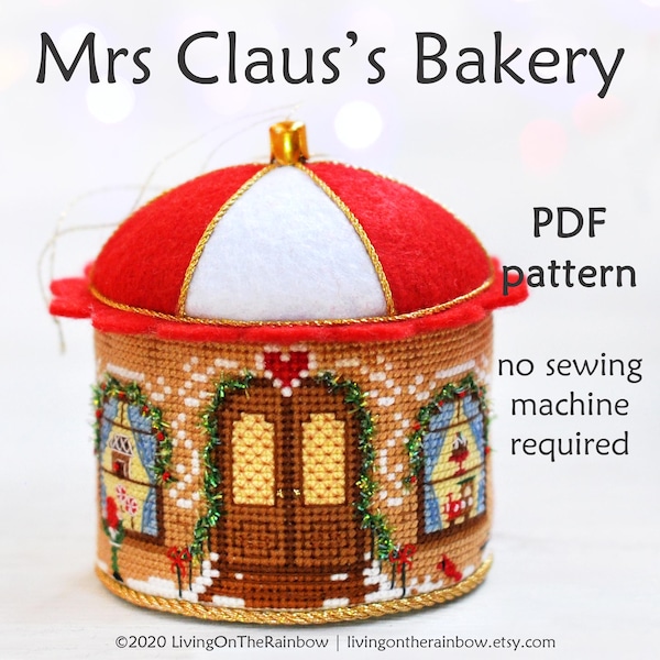 May include: A red and white felt gingerbread house ornament with a gold trim. The ornament is a PDF pattern for a no-sew project. The text "Mrs. Claus's Bakery" is at the top of the image. The text "PDF pattern" is on the right side of the image. The text "no sewing machine required" is below the text "PDF pattern".