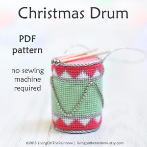 May include: A PDF pattern for a Christmas drum ornament. The drum is red, green, and silver with a white and silver trim. The pattern is for hand-stitching and does not require a sewing machine.