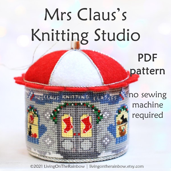 May include: A red and white felt pincushion shaped like a small building with a sign that reads "Mrs. Claus Knitting Classes". The pincushion is decorated with a wreath, stockings, and a cat. The text "PDF pattern, no sewing machine required" is also included in the image.