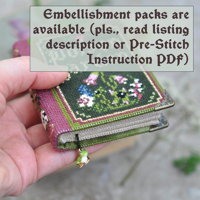 Op de afbeelding: Een klein, groen en paars boek met een bloemencross-stitch ontwerp. Het boek heeft een gouden bladwijzer met een groene kikkerbedel. De tekst op het boek luidt "Embellishment packs are available (pls., read listing description or Pre-Stitch Instruction PDF)".
