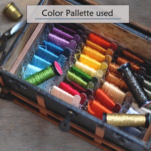 May include: A wooden box filled with colorful embroidery floss spools. The spools are arranged in rows, showcasing a wide array of colors including blues, greens, reds, oranges, and golds. The text "Color Palette used" is displayed above the box.