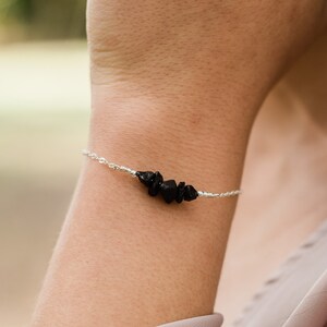 May include: A silver chain bracelet with a cluster of black gemstone chips.