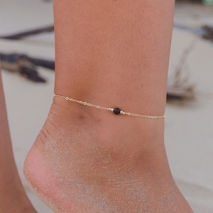 May include: A delicate gold anklet with a single black bead. 14K gold fill.