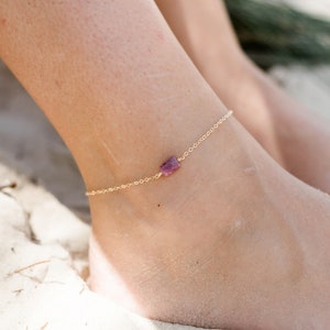 May include: A delicate gold anklet with a small, rectangular, pink gemstone charm. 14K Gold Fill.