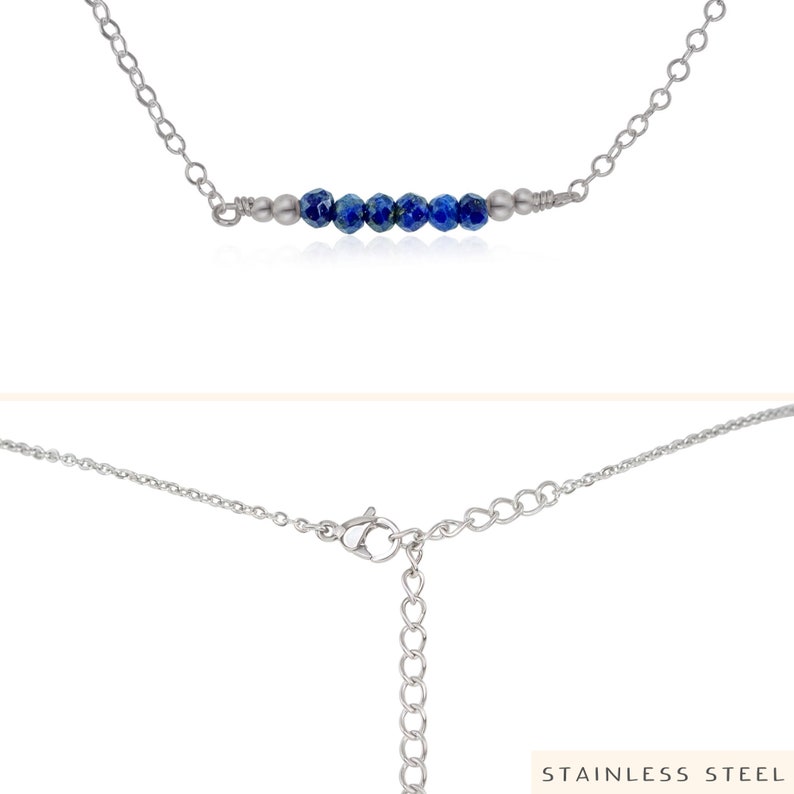 May include: A silver chain necklace with a row of blue gemstone beads. The necklace has a lobster claw clasp. "STAINLESS STEEL" is printed on the bottom of the image.