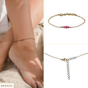 May include: A delicate gold anklet with a single pink gemstone. The anklet is shown on a model's ankle, with the word "BRONZE" visible in the bottom left corner of the image.