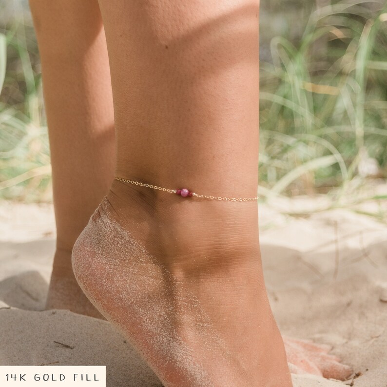 May include: A delicate gold anklet with a single pink gemstone bead. 14K Gold Fill.