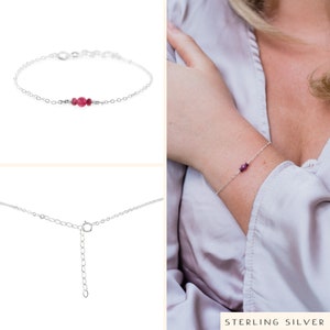 Puede incluir: Un delicado brazalete de cadena de plata con un peque&ntilde;o racimo de piedras preciosas rojas. El brazalete tiene un cierre de langosta.