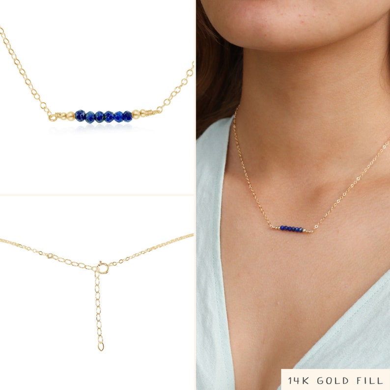 May include: A gold chain necklace with a row of small blue gemstone beads. The necklace has an adjustable clasp. 14K Gold Fill.