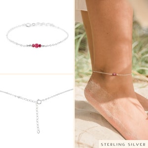 May include: Silver anklet with a small pink gemstone. The anklet has an adjustable clasp.