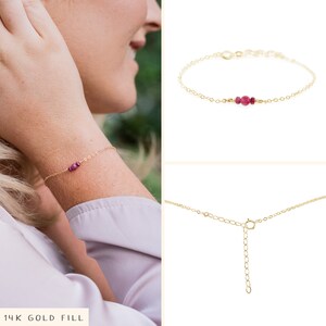 Puede incluir: Un delicado brazalete de cadena dorada con tres peque&ntilde;as piedras preciosas de color rosa oscuro. El brazalete tiene un cierre de langosta. 14K Gold Fill.