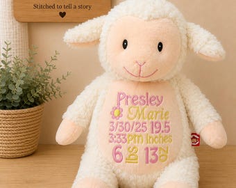 May include: A cream-colored plush lamb toy with a peach-colored face and belly. The belly features embroidered text reading Presley Marie, 3/30/25, 3:33PM, 19.5 Inches, and 6 lbs 13 oz, accented with a small pink flower and decorative stitching.