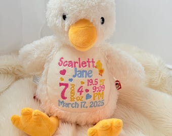 May include: A plush white duck toy with an orange beak and feet, featuring embroidered text on its belly: Scarlett Jane, 7 pounds 4 oz, 19.5 inches, 9:09 PM, and March 17, 2025, accompanied by small colorful heart and duck icons.