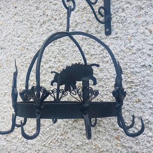 May include: Black metal pot rack with a silhouette of a pig on the top. The rack has multiple hooks for hanging pots and pans.