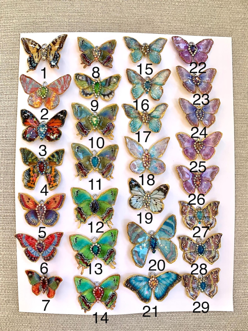 Puede incluir: Veintinueve abalorios de mariposa coloridos con detalles dorados. Cada abalorio tiene un dise&ntilde;o y una combinaci&oacute;n de colores diferentes. Los abalorios est&aacute;n numerados del 1 al 29.