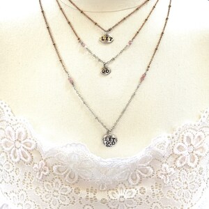 Puede incluir: Collar de capas con tres dijes de plata. Los dijes dicen "Let", "Go" y "Let God".