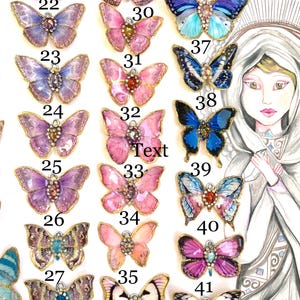 Puede incluir: Una colecci&oacute;n de 42 dijes de mariposa de resina con alas iridiscentes y detalles dorados. Las mariposas est&aacute;n dispuestas en filas y numeradas del 22 al 42. Las mariposas son todas de diferentes colores y patrones.