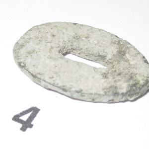 May include: A silver-colored metal ring with a rectangular hole in the center. The ring is slightly oval-shaped and has a rough, textured surface.