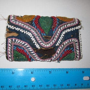 May include: A small, blue fabric pouch with a flap closure, decorated with colorful beads in a geometric pattern. The pouch is approximately 7 inches long and 4 inches wide.