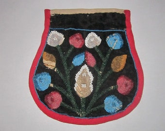 May include: A beaded pouch with a black background and a floral design. The flowers are white, blue, and red, and the leaves are green. The pouch is trimmed with red and blue beads.