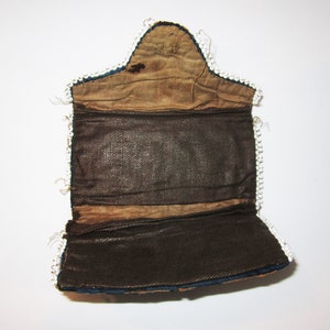 May include: A blue and brown fabric purse with a white beaded trim. The purse is open and the inside is lined with brown fabric.