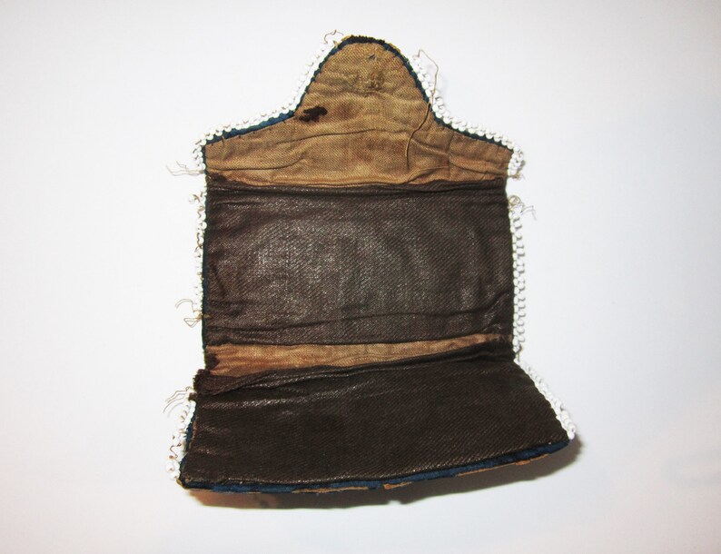 May include: A blue and brown fabric purse with a white beaded trim. The purse is open and the inside is lined with brown fabric.