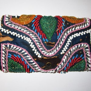 May include: A small, blue fabric pouch with a flap closure, decorated with colorful beads in a geometric pattern. The pouch has a metal clasp and is likely handmade.