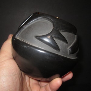 May include: Black pottery bowl with a geometric design. The bowl is hand-crafted and has a smooth, polished finish.