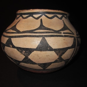 Puede incluir: Una jarra de cerámica tradicional nativa americana con un diseño geométrico en blanco y negro. La jarra está hecha de arcilla y tiene una forma redondeada.